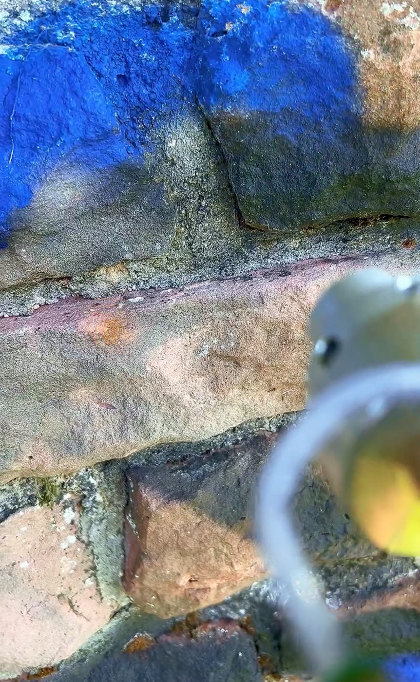 Feinstrahltechnik in Aktion – blaues Graffiti auf Sandstein wird mit Düse entfernt